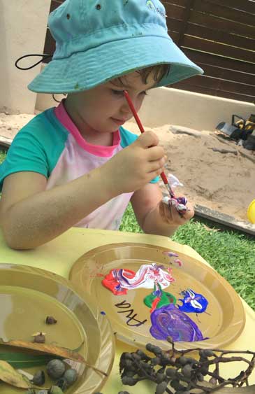 Ava creating some works of bush art using paint, gumnuts, leaves and clay.